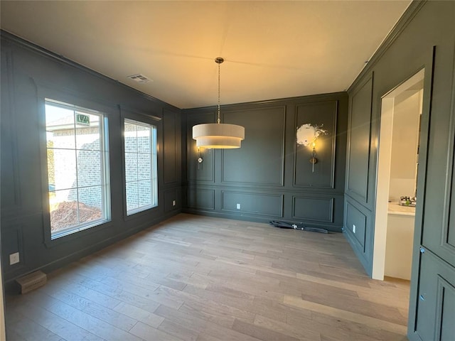 unfurnished dining area featuring ornamental molding, plenty of natural light, and light hardwood / wood-style floors