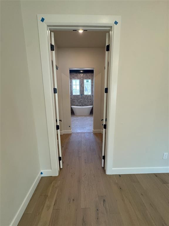 hall featuring light wood-style floors and baseboards