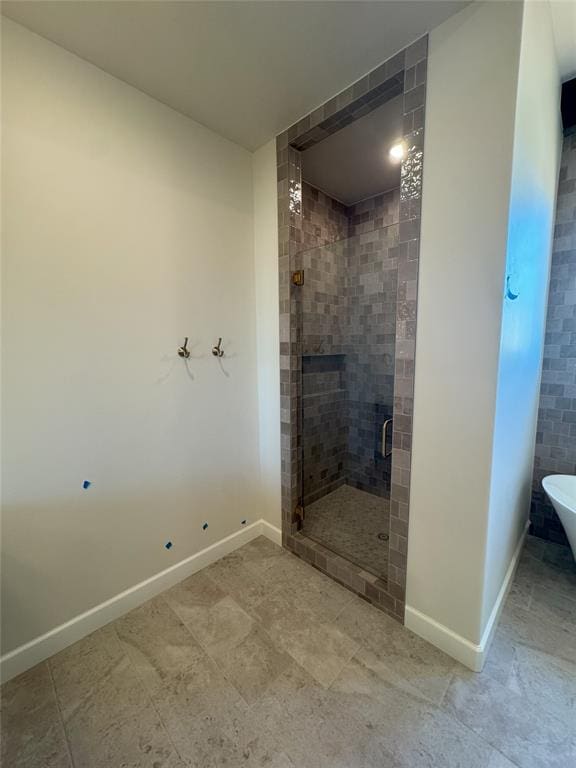 full bathroom featuring a freestanding bath, a fireplace, a shower stall, and baseboards