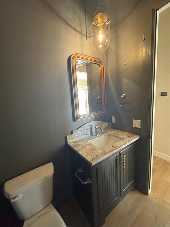 bathroom featuring vanity, wood finished floors, toilet, and baseboards