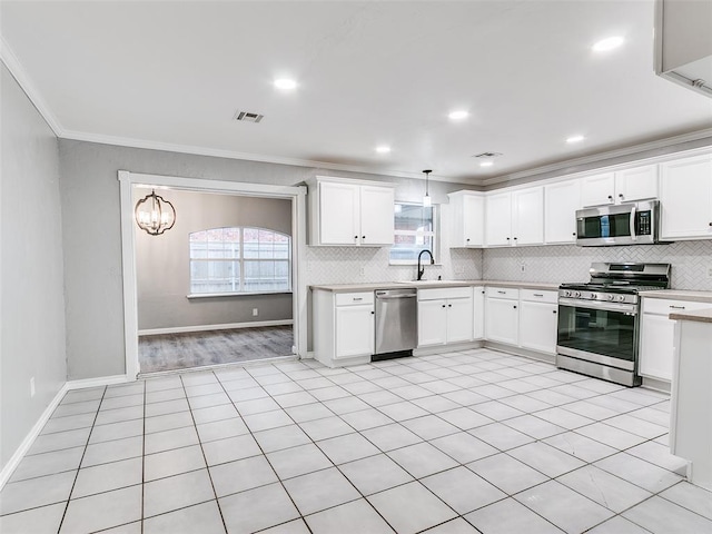 kitchen featuring white cabinets, decorative light fixtures, stainless steel appliances, and crown molding