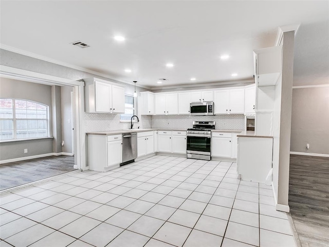 kitchen featuring appliances with stainless steel finishes, ornamental molding, sink, decorative light fixtures, and white cabinets