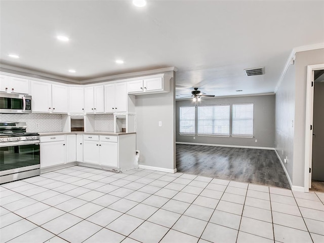 kitchen featuring ceiling fan, appliances with stainless steel finishes, decorative backsplash, white cabinets, and ornamental molding