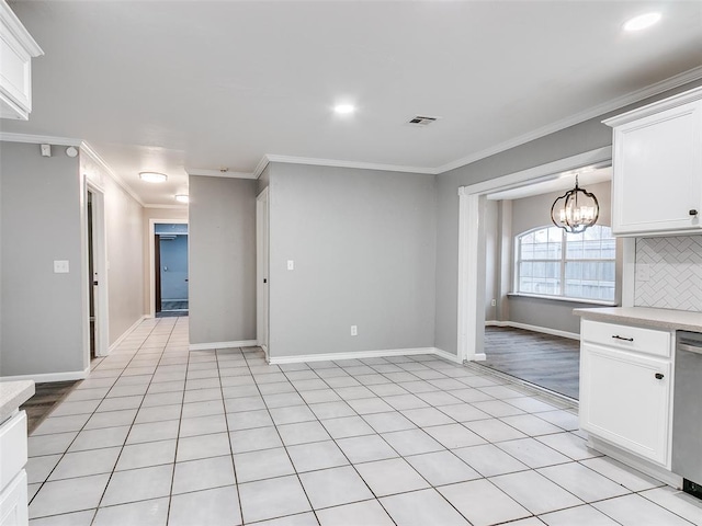 kitchen featuring decorative backsplash, crown molding, an inviting chandelier, dishwasher, and white cabinetry