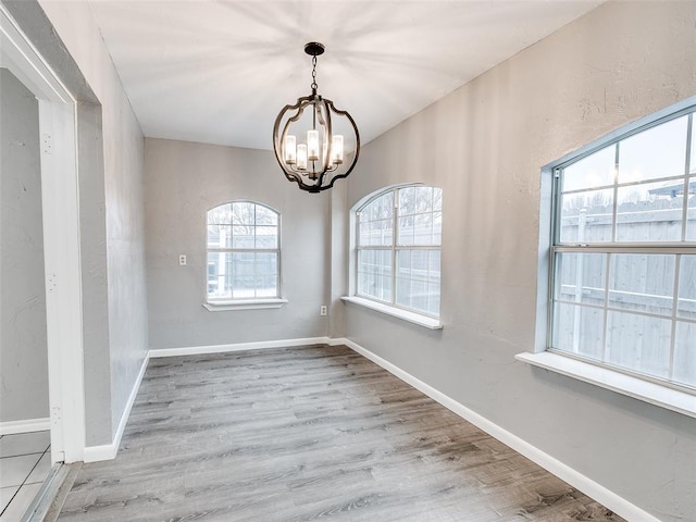 spare room with light hardwood / wood-style floors and an inviting chandelier