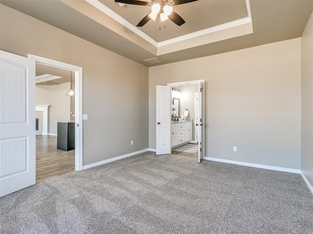 unfurnished bedroom with light colored carpet, connected bathroom, and a tray ceiling