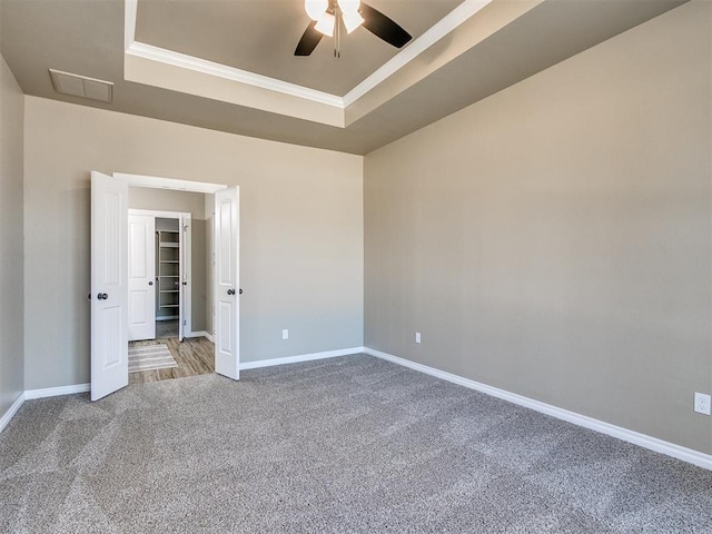 spare room with carpet flooring, ceiling fan, and a raised ceiling