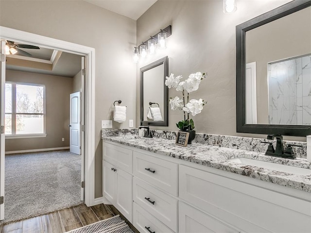 bathroom with vanity, ceiling fan, a raised ceiling, and ornamental molding