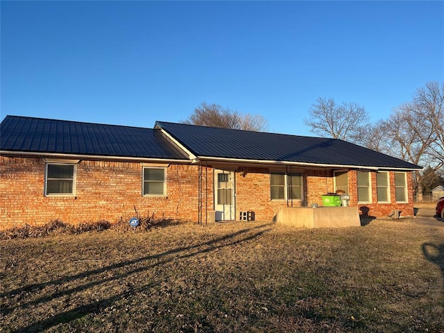 back of house with brick siding and metal roof
