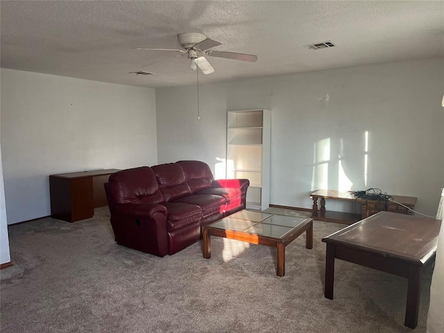 living room featuring ceiling fan, carpet flooring, and a textured ceiling