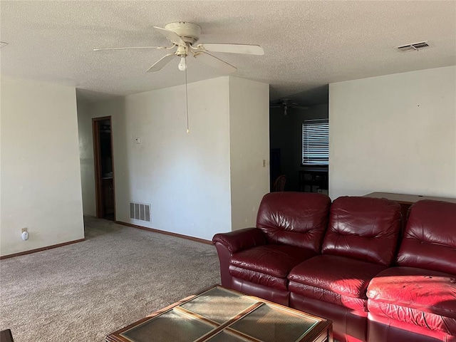 carpeted living room with ceiling fan and a textured ceiling