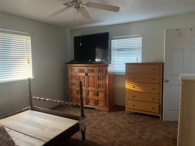 bedroom featuring ceiling fan, dark carpet, and a textured ceiling