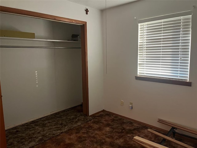 unfurnished bedroom with dark colored carpet and a closet