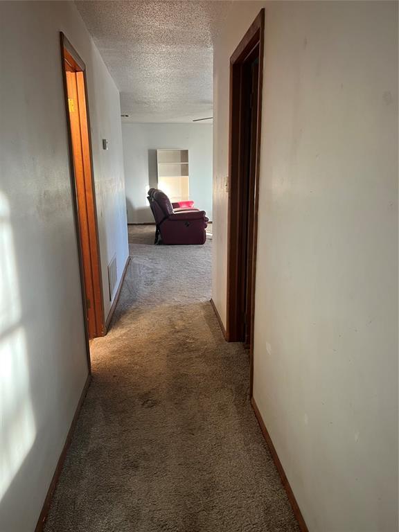 hallway with light colored carpet and a textured ceiling