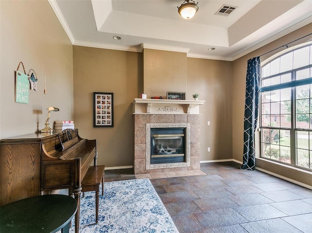 interior space featuring crown molding, a fireplace, and a tray ceiling