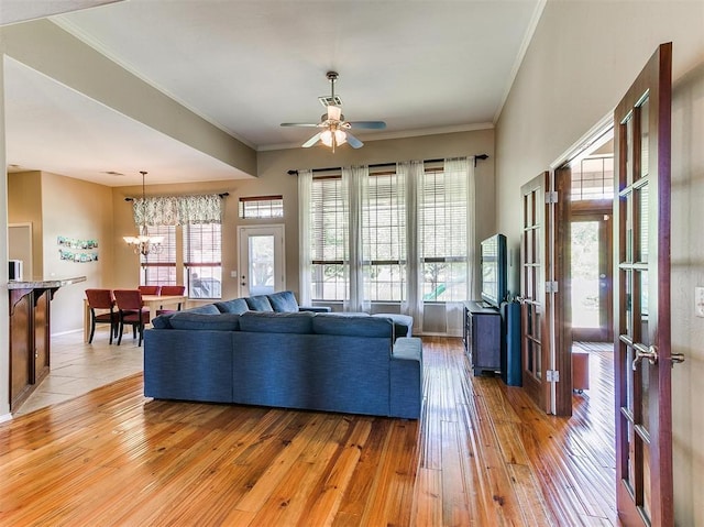 living room with french doors, ceiling fan with notable chandelier, light hardwood / wood-style flooring, and crown molding