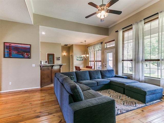 living room featuring ceiling fan with notable chandelier, light wood-type flooring, crown molding, and a wealth of natural light