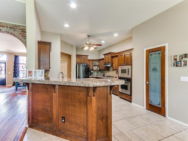 kitchen featuring a breakfast bar area, kitchen peninsula, light tile patterned floors, and appliances with stainless steel finishes