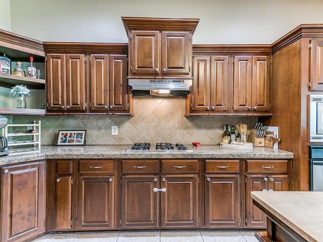 kitchen featuring decorative backsplash, light tile patterned floors, oven, and stainless steel gas stovetop