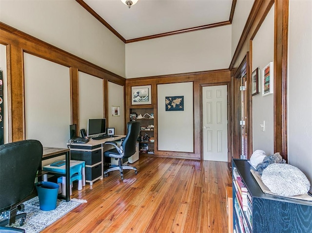 office with crown molding, light hardwood / wood-style flooring, and a high ceiling