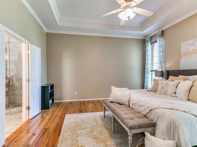 bedroom with a raised ceiling, ensuite bath, ceiling fan, and light hardwood / wood-style floors