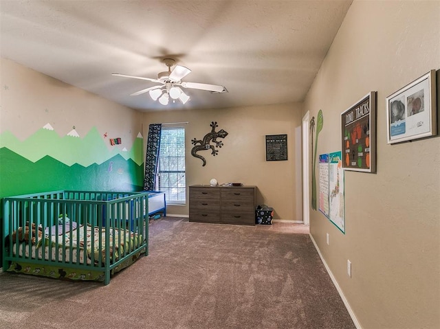 carpeted bedroom with ceiling fan and a crib