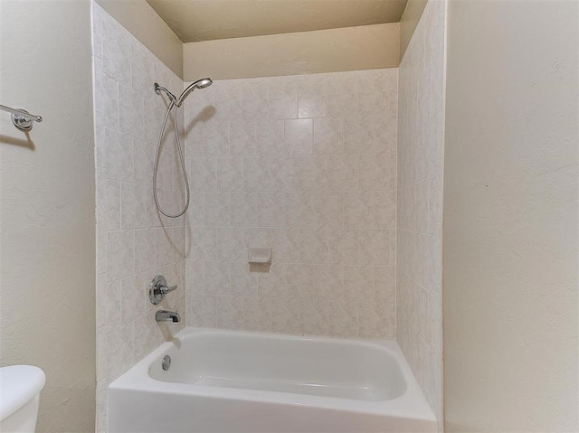 bathroom with toilet and tiled shower / bath