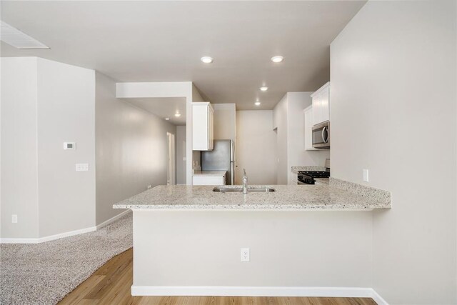 5435 Mac Rd, Tuttle, OK 73089 - kitchen featuring white cabinets, sink, light hardwood / wood-style flooring, appliances with stainless steel finishes, and kitchen peninsula