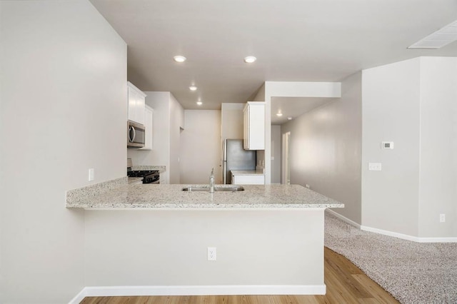 kitchen with kitchen peninsula, stainless steel appliances, white cabinets, and sink