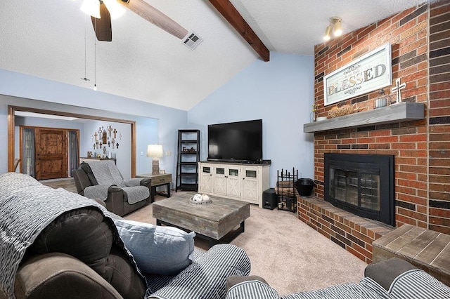 carpeted living room with ceiling fan, a fireplace, lofted ceiling with beams, and a textured ceiling