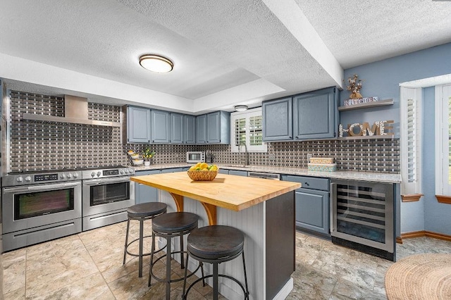 kitchen with beverage cooler, wood counters, double oven range, a breakfast bar, and a kitchen island