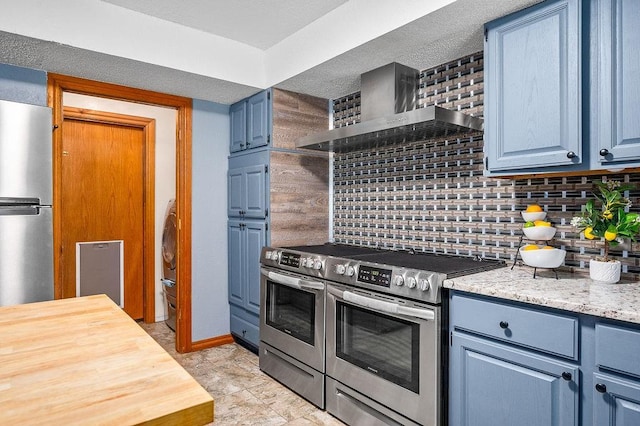 kitchen featuring backsplash, blue cabinetry, wall chimney exhaust hood, and stainless steel appliances