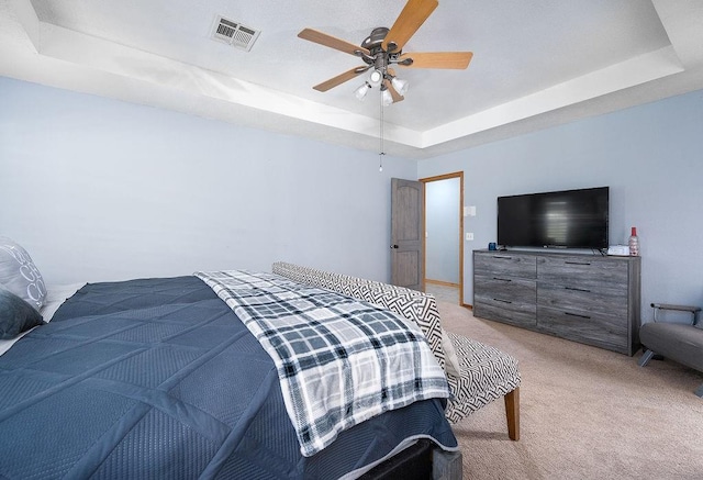 bedroom with light carpet, a raised ceiling, and ceiling fan