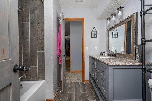 full bathroom with vanity, toilet, a textured ceiling, and tiled shower / bath combo