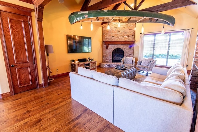 living room featuring vaulted ceiling with beams, wood-type flooring, and a fireplace