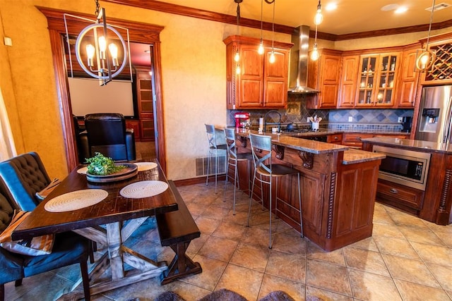 kitchen featuring wall chimney exhaust hood, decorative light fixtures, and appliances with stainless steel finishes