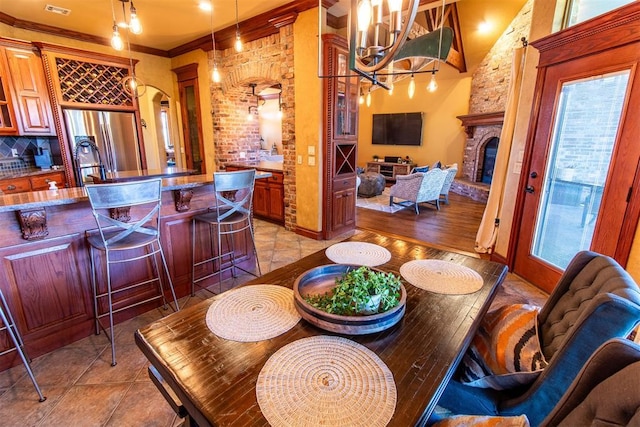 dining room featuring a notable chandelier, ornamental molding, and a fireplace