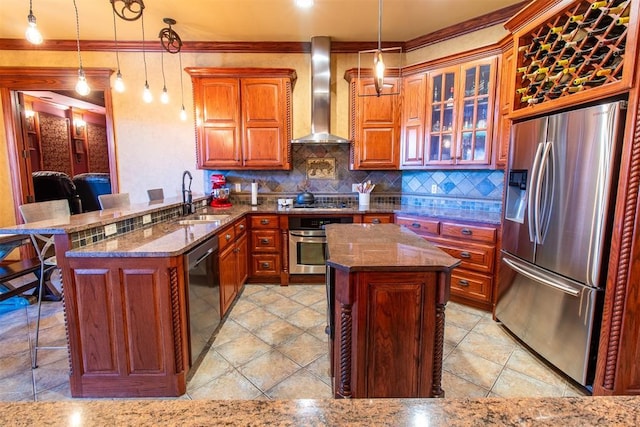 kitchen featuring a kitchen breakfast bar, stainless steel appliances, hanging light fixtures, and wall chimney range hood