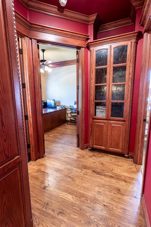 hallway with crown molding and light wood-type flooring