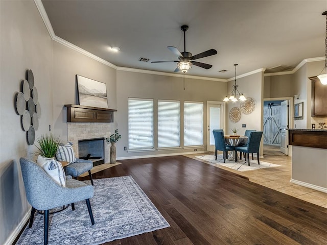 living room with crown molding, ceiling fan with notable chandelier, and light wood-type flooring