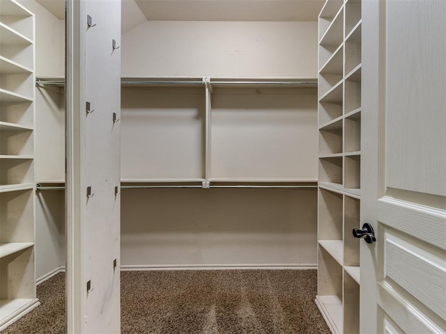 spacious closet featuring dark carpet and lofted ceiling