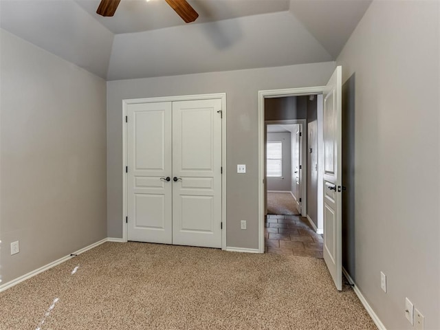 unfurnished bedroom with light colored carpet, a closet, lofted ceiling, and ceiling fan