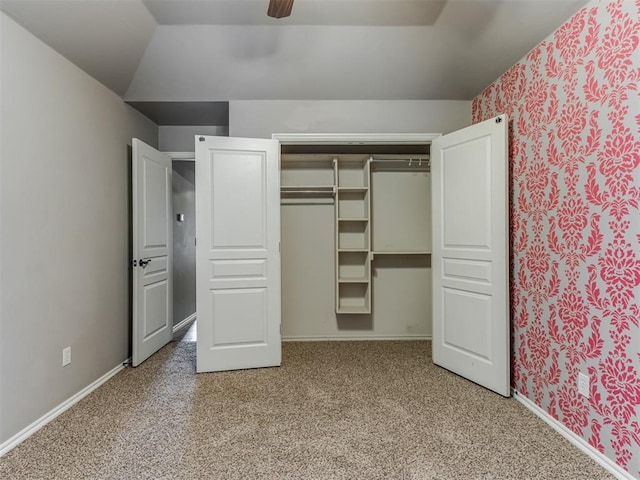 unfurnished bedroom featuring ceiling fan, light colored carpet, lofted ceiling, and a closet