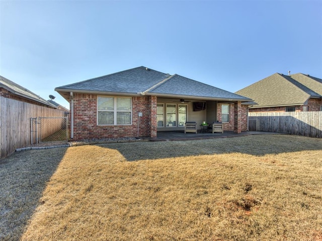 rear view of house with ceiling fan, a patio area, and a lawn