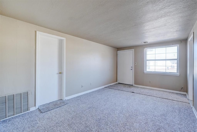 unfurnished room with carpet floors and a textured ceiling