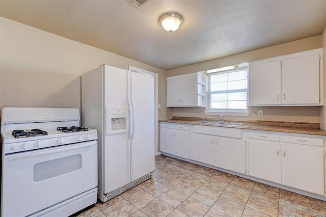 kitchen with white appliances, white cabinetry, and sink