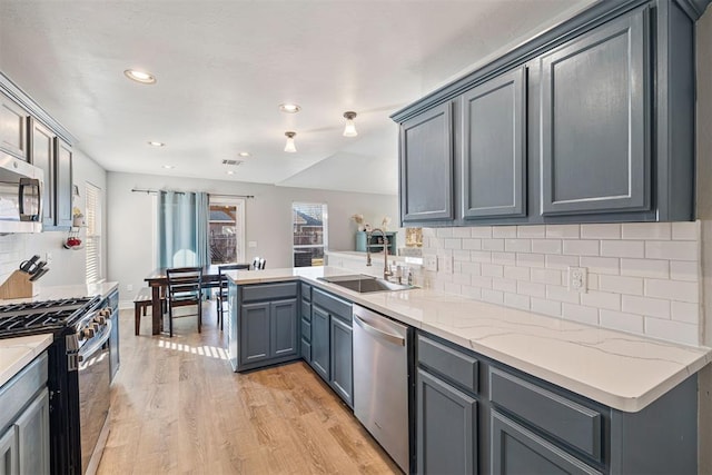 kitchen with gray cabinets, sink, stainless steel appliances, and light hardwood / wood-style flooring