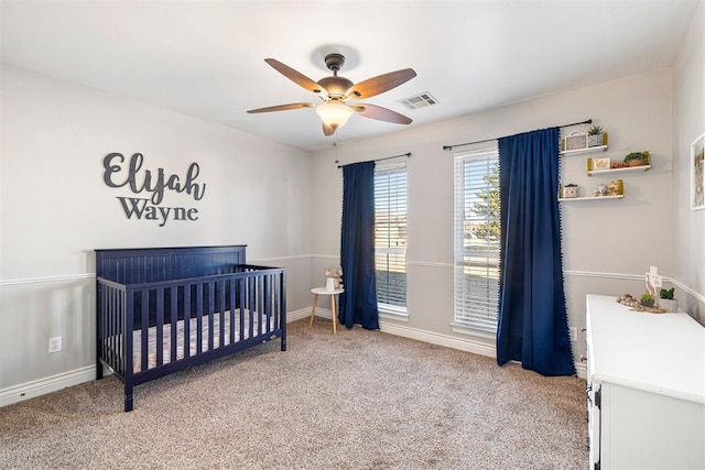 carpeted bedroom with ceiling fan and a nursery area