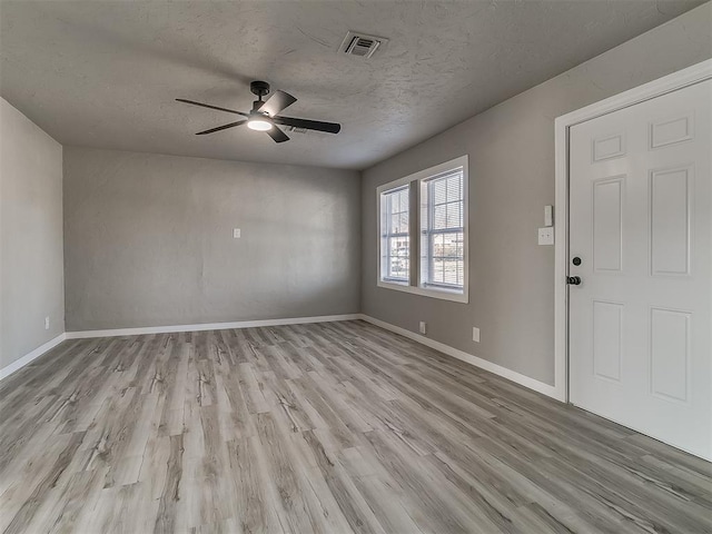 unfurnished room with ceiling fan, light wood-type flooring, and a textured ceiling