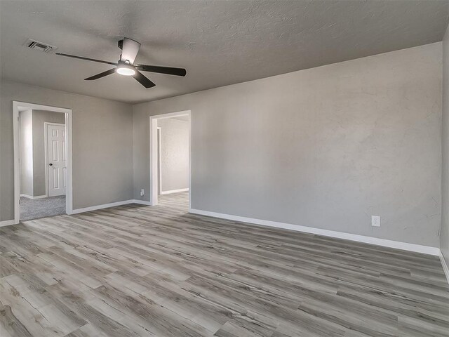 unfurnished room featuring ceiling fan, a textured ceiling, and light wood-type flooring